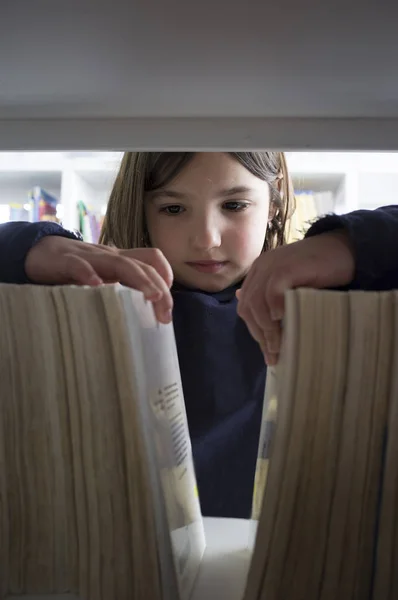 Giovane ragazza che seleziona i libri dalla libreria biblioteca — Foto Stock