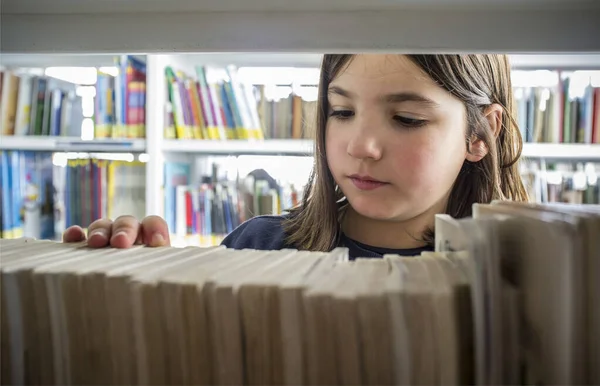 Giovane ragazza che seleziona i libri dalla libreria biblioteca — Foto Stock