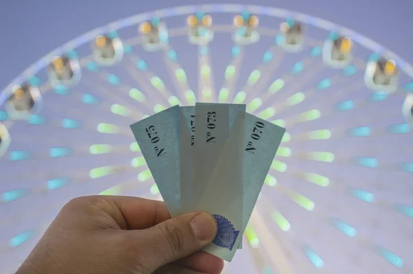 Main avec une poignée de billets pour la roue ferris géant attractio — Photo