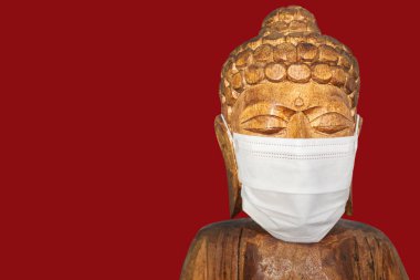 Yüz maskesi takan Buda heykeli. Kırmızıda izole edilmiş. Covid-19 konsepti