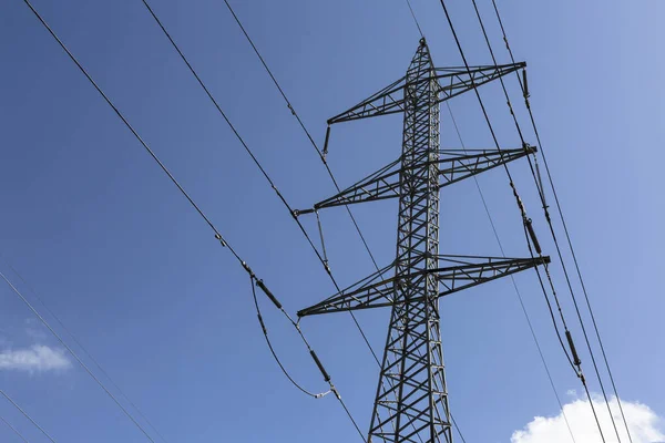 Electric pole with high voltage electric wires against the blue sky