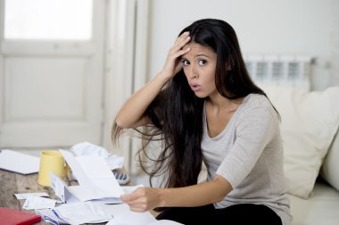 young attractive latin woman at home living room couch calculating monthly expenses worried in stress