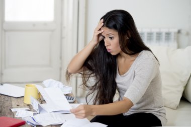 young attractive latin woman at home living room couch calculating monthly expenses worried in stress