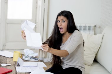 young attractive latin woman at home living room couch calculating monthly expenses worried in stress