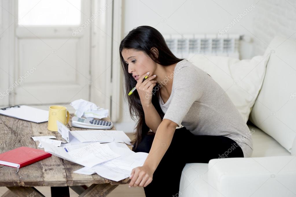 young attractive latin woman at home living room couch calculating monthly expenses worried in stress