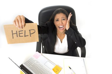 young busy desperate Latin businesswoman holding help sign sitting at office desk in stress worried