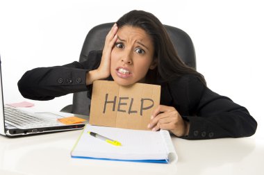 young busy desperate Latin businesswoman holding help sign sitting at office desk in stress worried