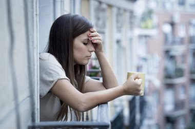 young sad beautiful woman suffering depression looking worried and wasted on home balcony