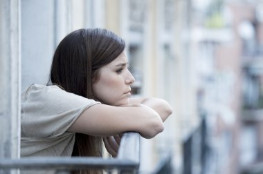 young sad beautiful woman suffering depression looking worried and wasted on home balcony
