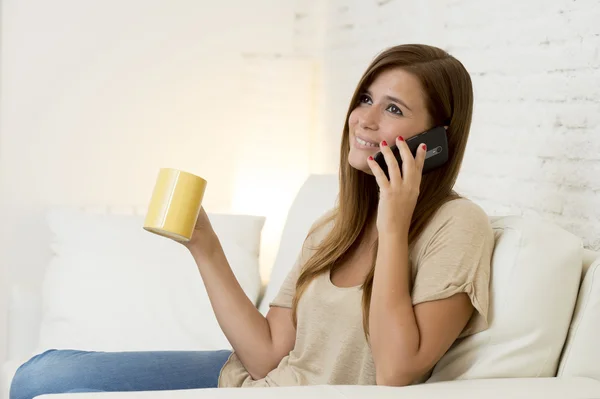 Happy beautifu woman on couch talking on mobile phone relaxed and cheerful smiling at home sofa — ストック写真