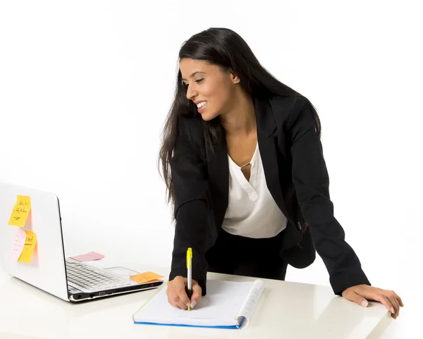 Attractive hispanic businesswoman or secretary taking notes standing leaning on office computer desk — Stock Photo, Image