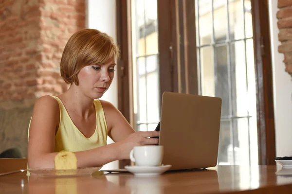 Mulher trabalhando ocupado no café com computador portátil usando telefone celular — Fotografia de Stock