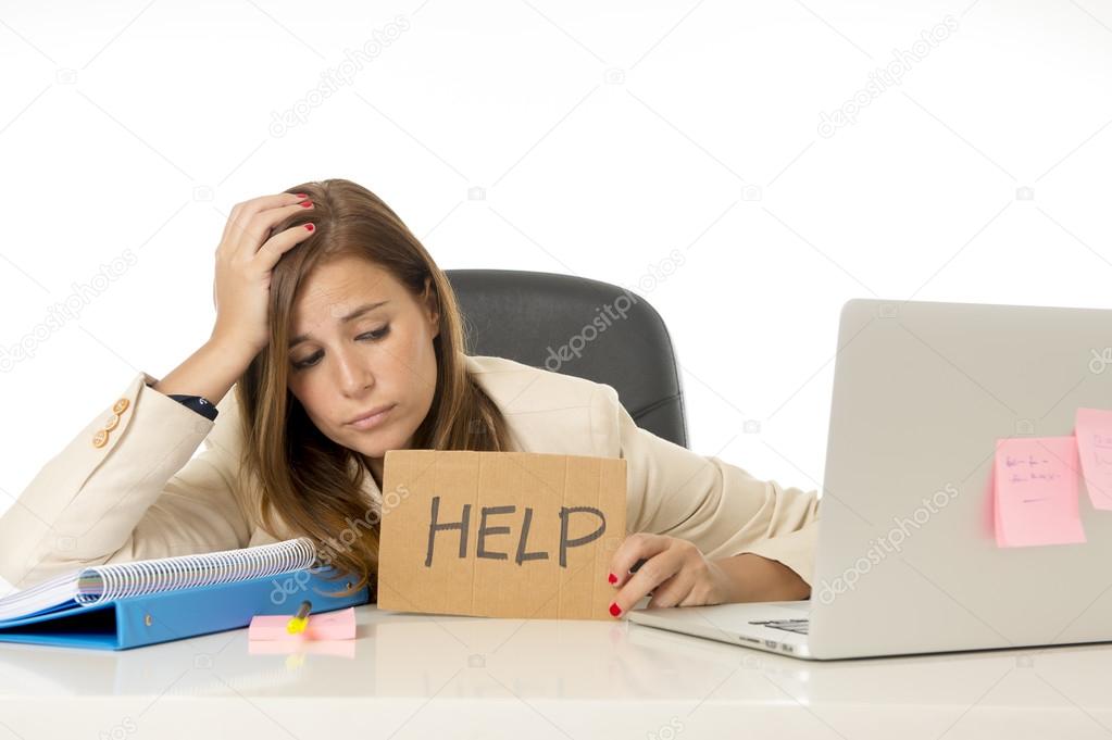 sad desperate businesswoman in stress at office computer desk holding help sign