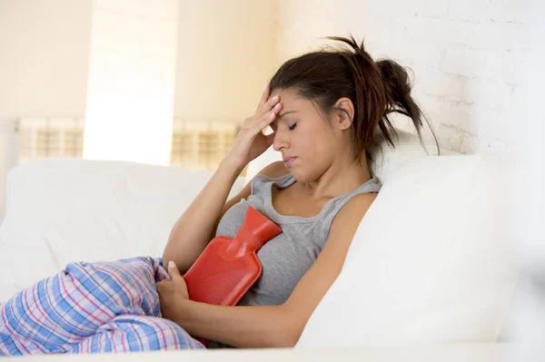 Joven hermosa mujer hispana sosteniendo botella de agua caliente contra el vientre sufriendo dolor menstrual período — Foto de Stock