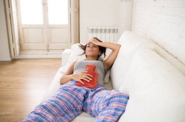 adet dönemi acı göbek karşı sıcak su şişesi tutan genç güzel İspanyol kadın