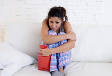 adet dönemi acı göbek karşı sıcak su şişesi tutan genç güzel İspanyol kadın