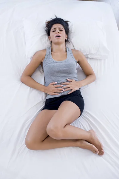 Hermosa mujer hispana en dolorosa expresión sosteniendo vientre sufrimiento menstrual período dolor — Foto de Stock