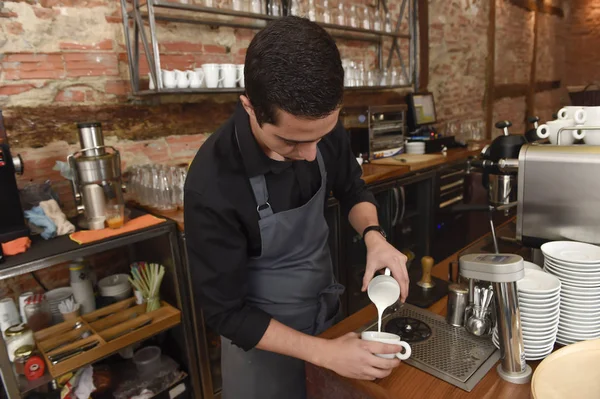 Joven barista italiano o cafetera en la tienda de restaurantes preparando crema de leche en la máquina de café — Foto de Stock