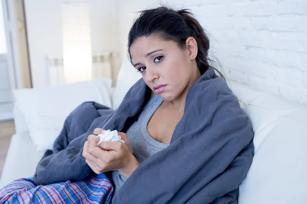 Wanita muda hispanik menarik terbaring sakit di sofa rumah dalam dingin dan flu dalam gejala penyakit gripe — Stok Foto