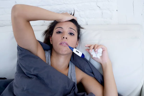 Jovem atraente hispânico mulher deitada doente em casa sofá no frio e gripe em gripe doença sintoma — Fotografia de Stock