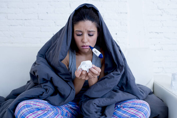 young attractive hispanic woman lying sick at home couch in cold and flu  in gripe disease symptom