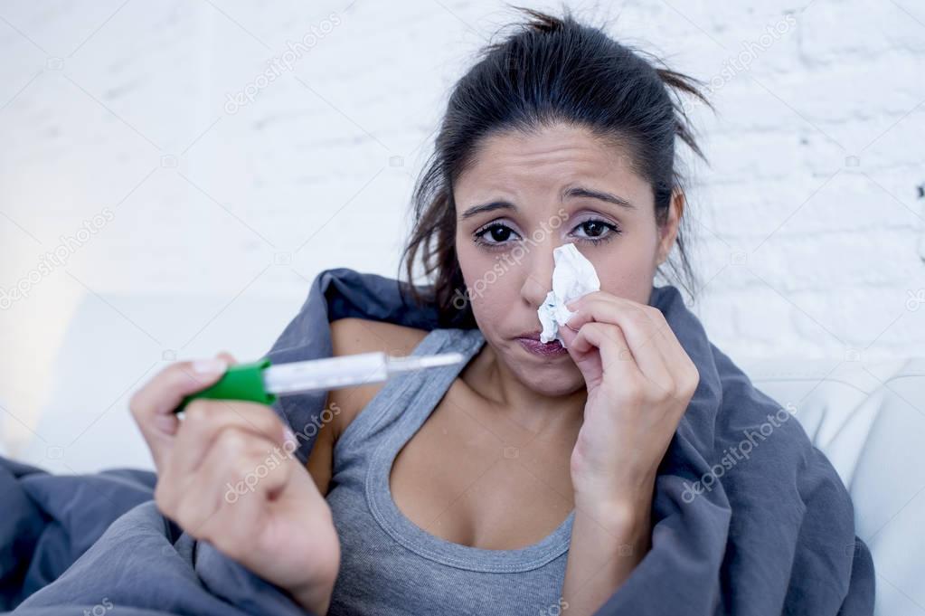 young attractive hispanic woman lying sick at home couch in cold and flu  in gripe disease symptom