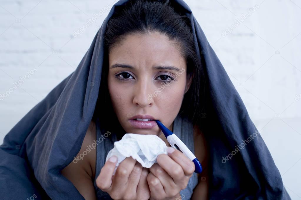 young attractive hispanic woman lying sick at home couch in cold and flu  in gripe disease symptom