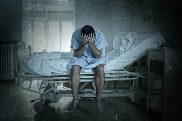 Відчайдушний чоловік сидить у лікарняному ліжку один сумний і спустошений страждає депресія плаче в клініці — стокове фото