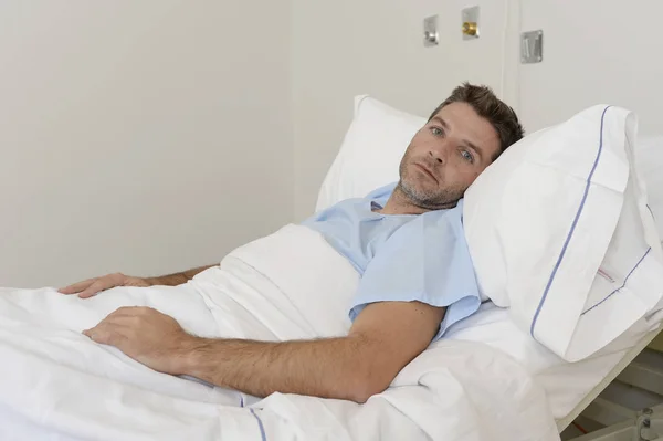 Giovane uomo paziente sdraiato a letto d'ospedale a riposo stanco cercando triste e depresso preoccupato — Foto Stock