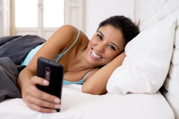 Hispânico mulher relaxado usando internet telefone celular enviando mensagem em casa quarto sorrindo feliz — Fotografia de Stock