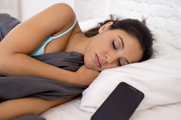 Женщина спит в постели дома вместе с мобильным телефоном в интернет-зависимости сети — стоковое фото