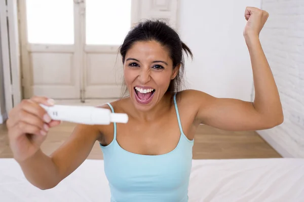 Bela mulher latina segurando teste de gravidez olhando e encontrar resultado positivo sorrindo feliz e animado — Fotografia de Stock