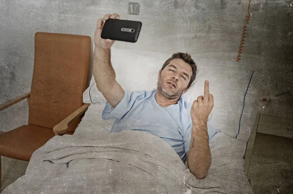 Man lying on bed hospital clinic holding mobile phone taking self portrait selfie photo sad depressed — Stock Photo, Image