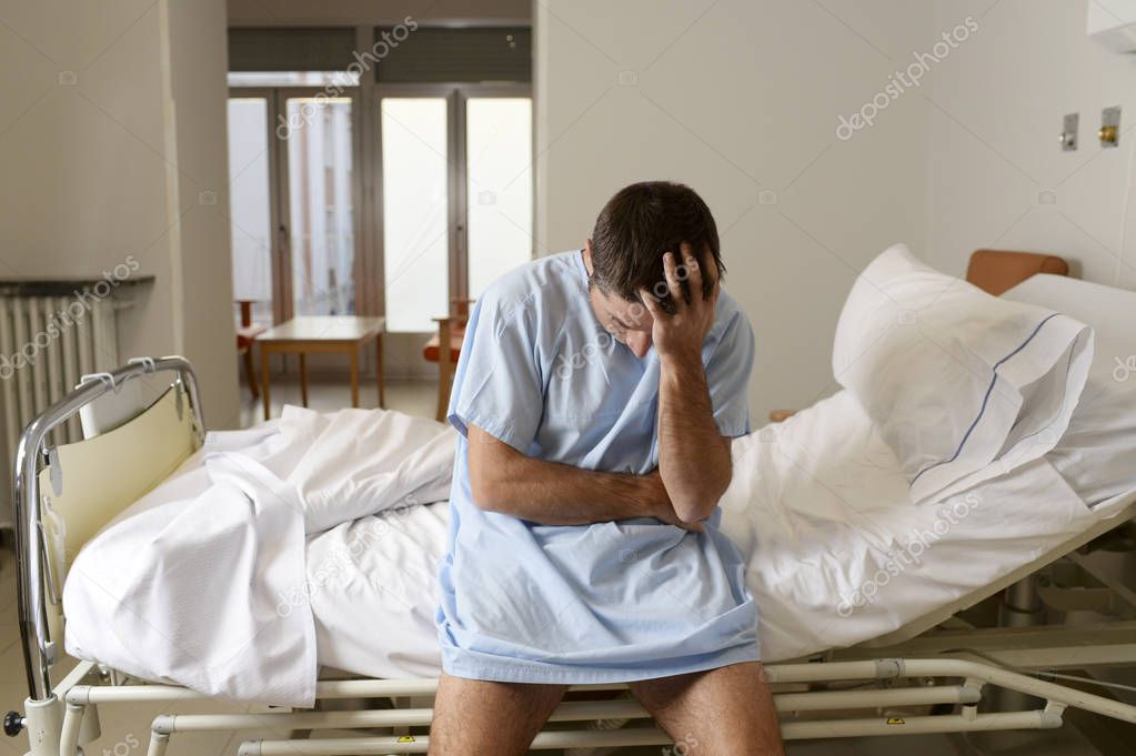 Desperate man sitting at hospital bed alone sad and devastated s Stock