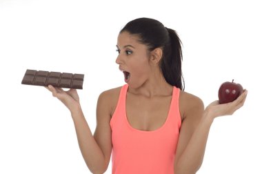 genç çekici İspanyol kadın fitness üst elma meyve ve çikolata onun elinde tutan