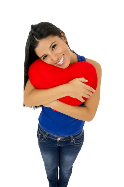 Giovane donna bella e felice con in mano cuscino rosso a forma di cuore sorridente isolato in bianco — Foto Stock