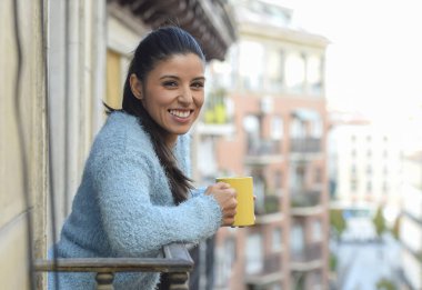 latin kadın fincan kahve ya da çay gülümseyerek mutlu daire pencere balkon içme 
