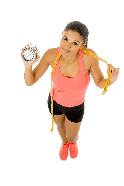 Mujer hispana sosteniendo el despertador y Taylor miden la cinta a tiempo para el deporte y el concepto de dieta — Foto de Stock