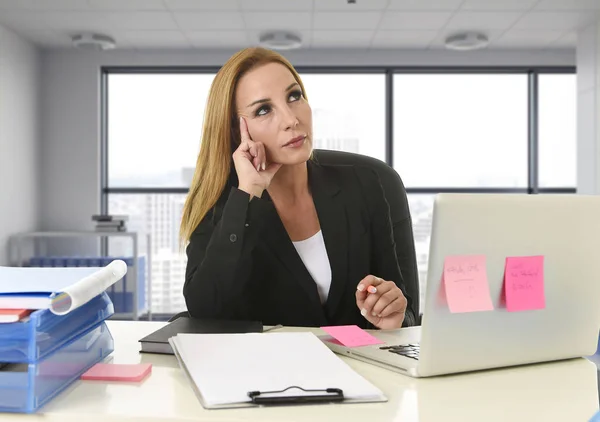 Woman working at  laptop computer sitting on the desk absent minded and thoughtful sitting at business district office — Stock Photo, Image
