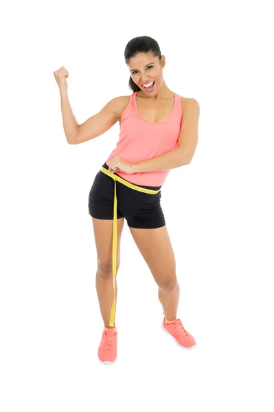 Schöne lateinische Frau in Fitnessbekleidung, die Körpertaillengröße misst, Maßband hält und glücklich lächelt — Stockfoto