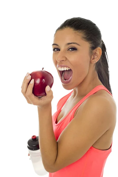 L mujer del deporte latino en ropa de fitness comiendo fruta de manzana sonriendo feliz en una nutrición saludable —  Fotos de Stock