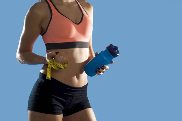 Deporte mujer celebración botella de agua y medir cinta mostrando delgado perfecto abdominales y estómago — Foto de Stock