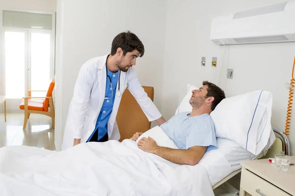 Doctor consulting patient lying on hospital bed talking about the diagnose and treatment in modern clinic — Stock Photo, Image