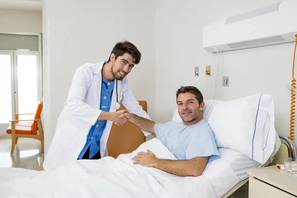 Γιατρού συμβουλευτικές ασθενή ξαπλωμένο στο κρεβάτι του νοσοκομείου που απελευθερώνεται κουνώντας τα χέρια στην σύγχρονη κλινική — Φωτογραφία Αρχείου