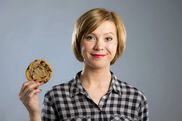 Mladá blond roztomilý a přátelské Kavkazský žena v neformálním oblečení drží velké lahodné čokolády cookie — Stock fotografie