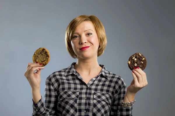 Молодая блондинка милая и дружелюбная кавказка в повседневной одежде с двумя большими шоколадными печеньями — стоковое фото