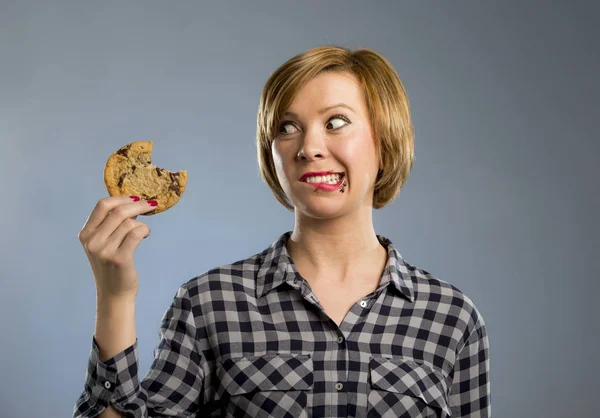 Leuke mooie vrouw met chocolade vlek in mond eten grote heerlijke cookie — Stockfoto
