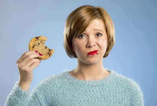 Roztomilá krásná žena s čokoládovou skvrny v ústech jíst velké lahodné cookie — Stock fotografie