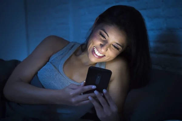 Девушка в постели с помощью мобильного телефона поздно ночью в темной спальне лежал счастливым и расслабленным — стоковое фото