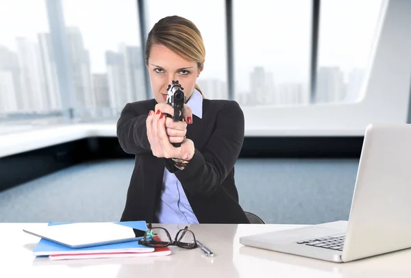 Empresária sentado na mesa do escritório apontando arma em poderoso b — Fotografia de Stock